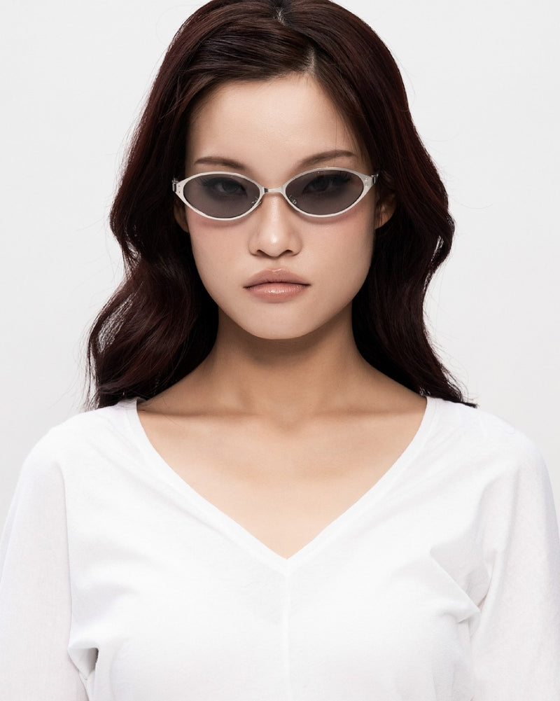 A model facing the camera in SEEYAA! slim silver oval sunglasses with grey lenses.