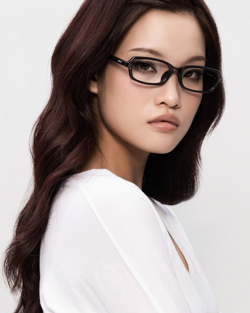 A model in SEEYAA! dark rectangular acetate optical frames, head turned to the side.